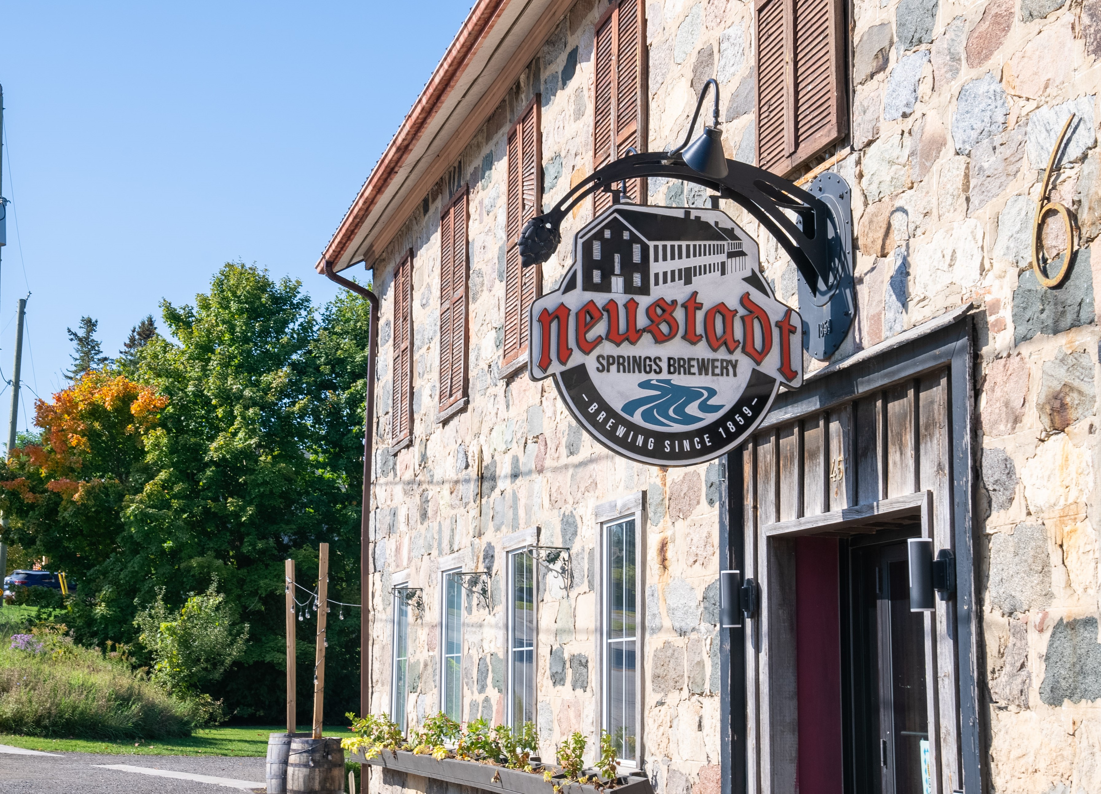 Exterior of a stone building. Sign reads Neustadt Springs Brewery.