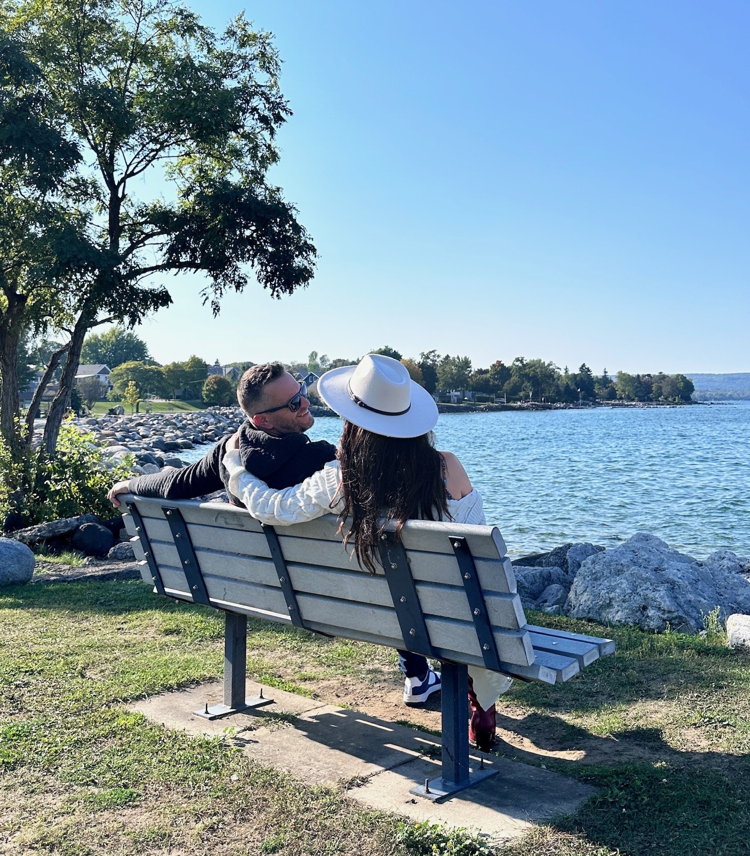 a couple sitting on a bench by the water
