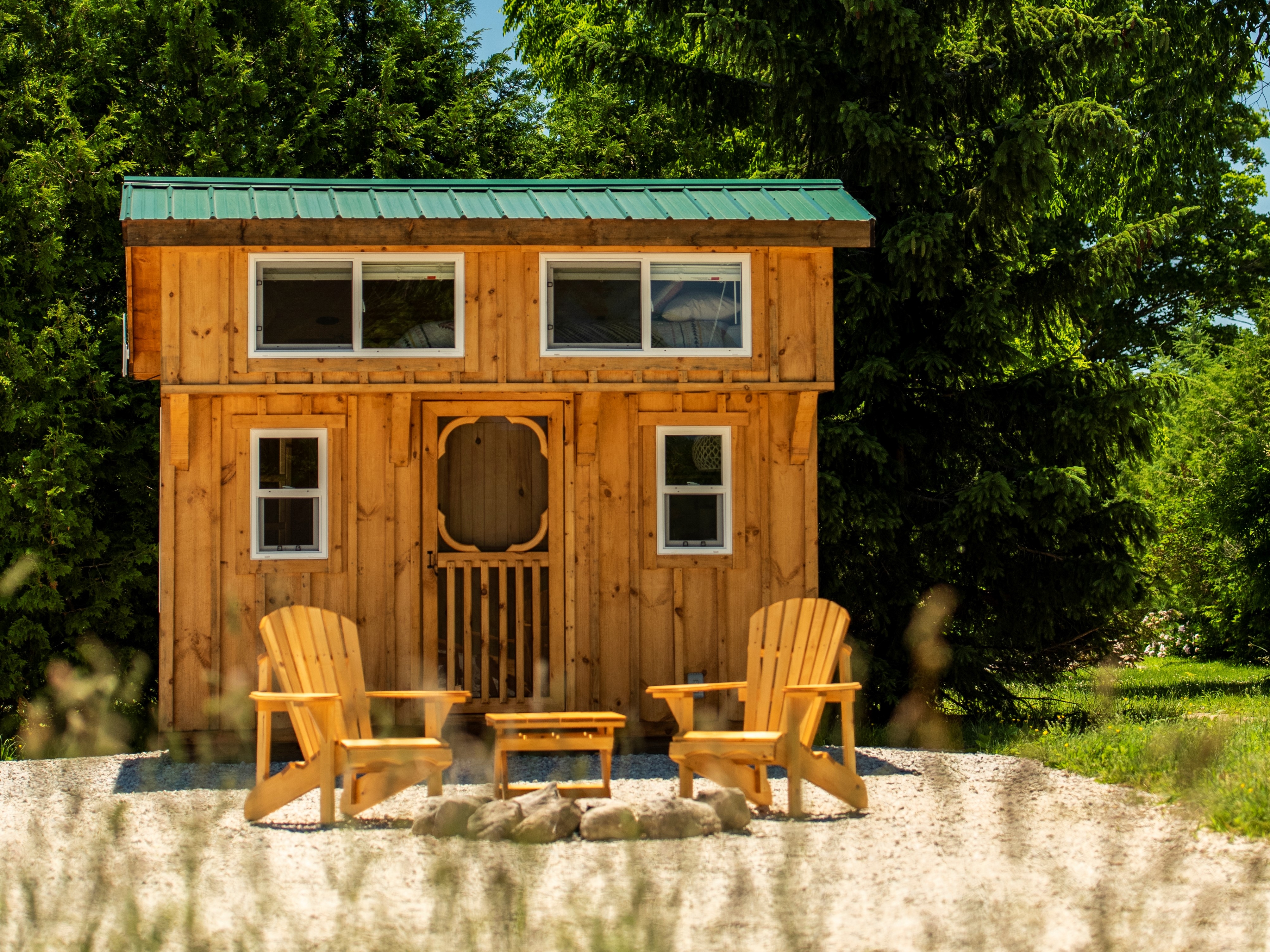 Exterior of cabin with two muskoka chairs and nature surrounding