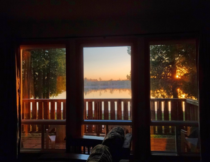 Interior of cottage looking outside to lake across deck