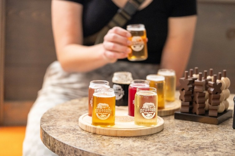 A woman sitting at a table with a flight of beers on it