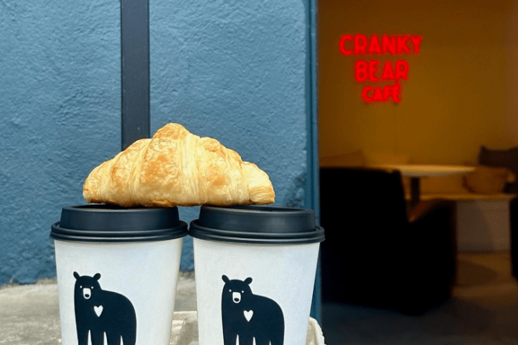 Cranky Bear Café Cranky Bear coffee cups and croissant in front of their café