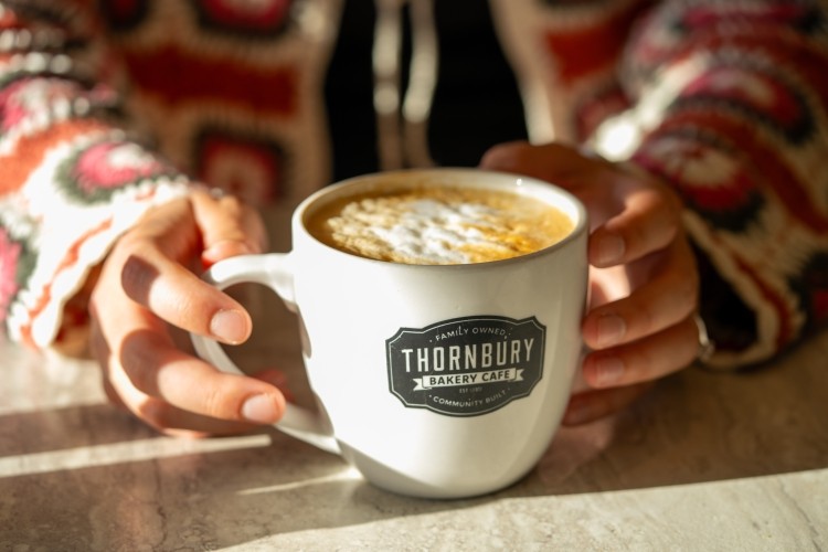 Thornbury Bakery Café Someone holding a thornbury cafe coffee cup