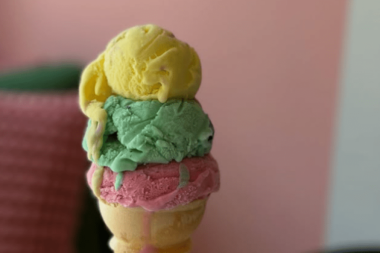 Three scoops of colorful ice cream in a cone