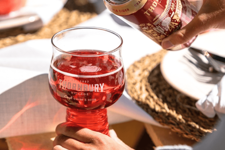 someone pouring a cider into a glass