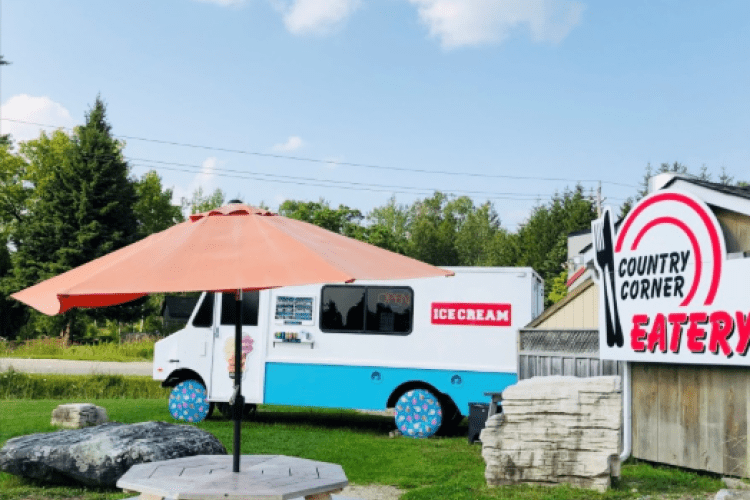 A picnic table with umbrella outside of Country Corner Eatery
