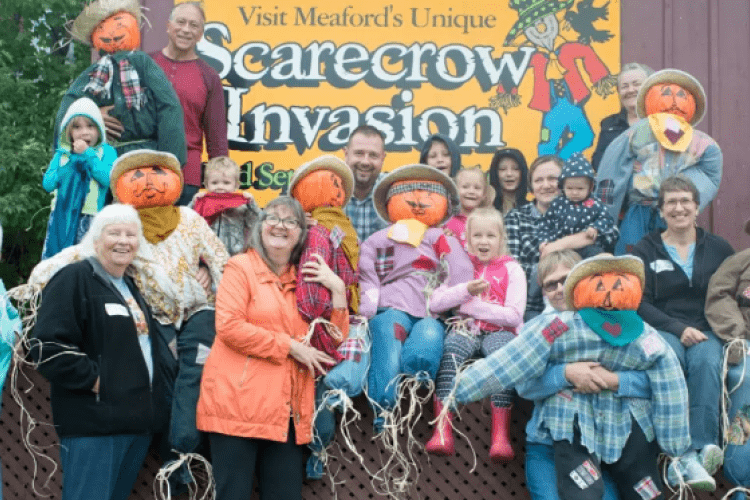 People gathered around with scarecrows 