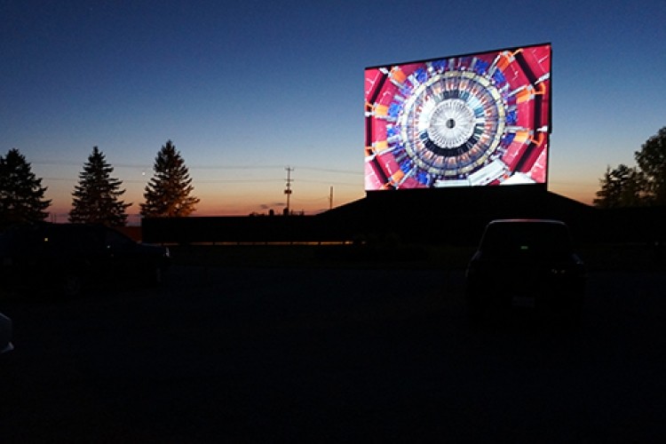 Movie on drive in screen at sunset
