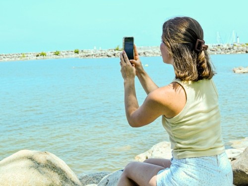 a girl taking a photo of the waterfront